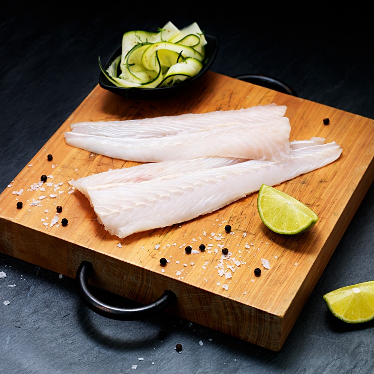 Hokifilé på skärbräda med lime och svartpepparkorn